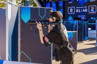Боец LASERWAR прицеливается из-за синего укрытия.