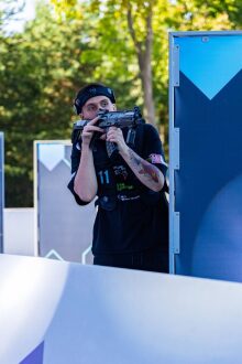 Игрок LASERWAR целится из-за укрытия, готовясь к выстрелу.