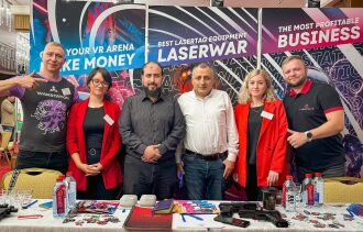 Команда LASERWAR позирует на фоне баннеров.