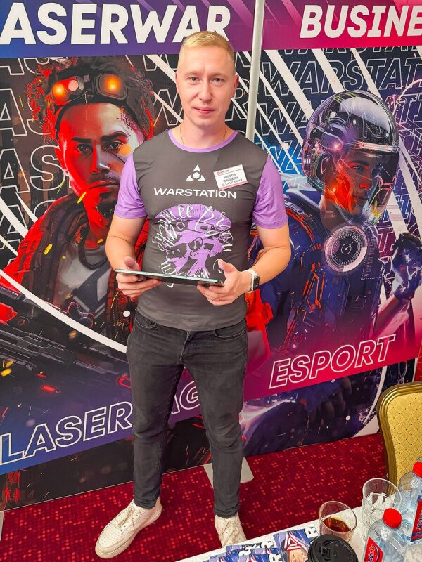 Мужчина держит планшет на фоне футуристичных баннеров LASERWAR.