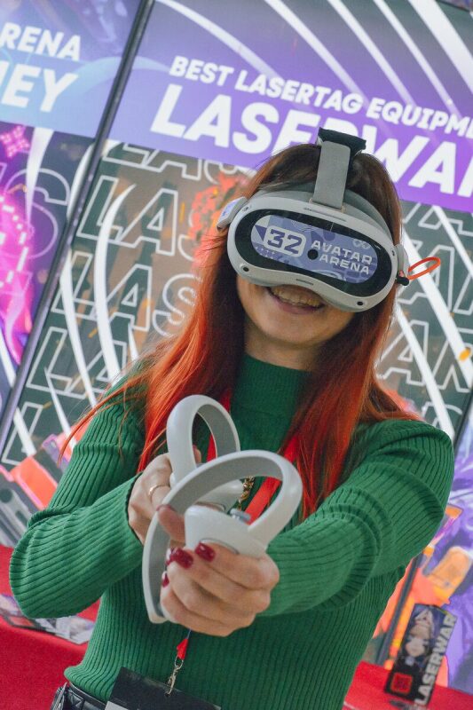 Девушка с VR-гарнитурой и контроллерами готова к игре.