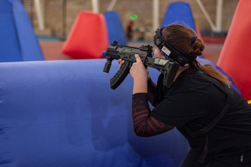 Игрок LASERWAR с автоматом укрывается за препятствием.