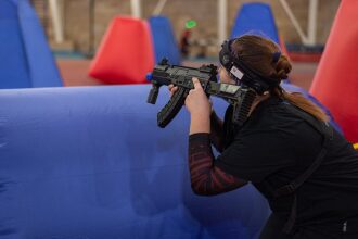 Игрок LASERWAR с автоматом укрывается за препятствием.