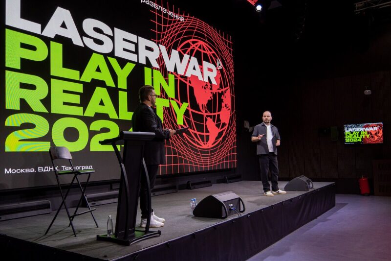 Два спикера LASERWAR на сцене перед огромным экраном.
