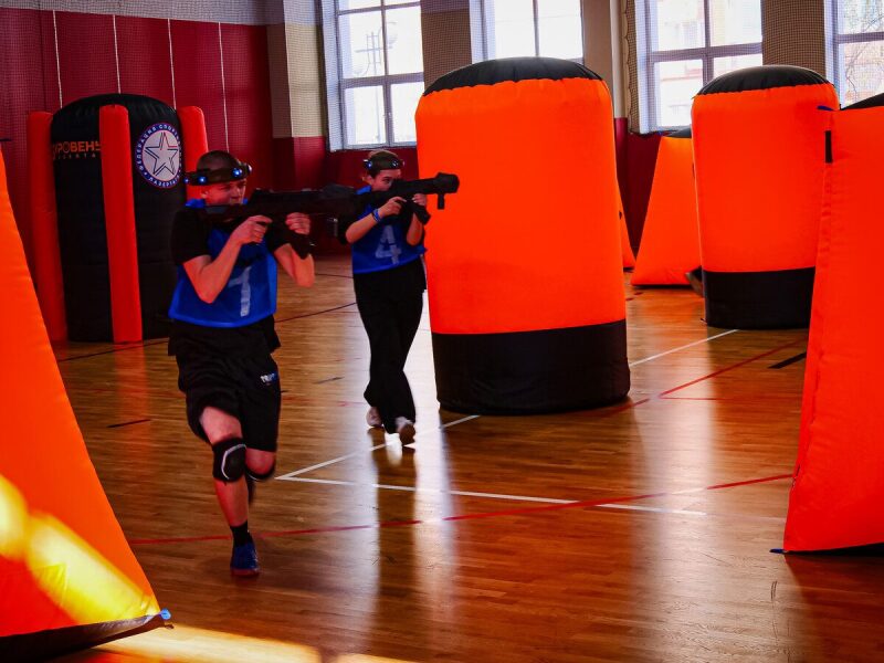 Игроки LASERWAR в движении с оружием на арене.