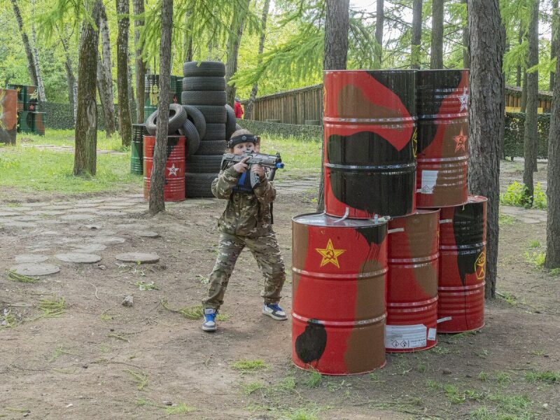 Мальчик в камуфляже ведет прицельный огонь из бластера.
