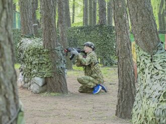 Юный боец LASERWAR занял позицию у ствола дерева.