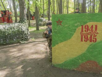 Мальчик в камуфляже целится из-за стены с датами