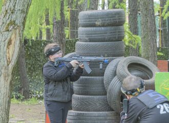 Юный лазертаг-боец LASERWAR прицеливается из-за шин.