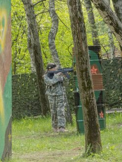 Юный боец LASERWAR ведет прицельный огонь из-за бочек.