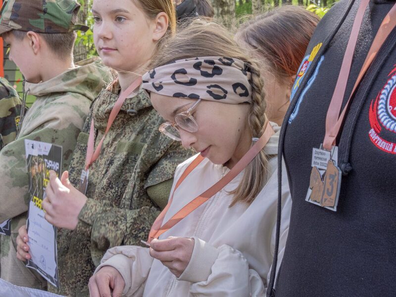 Девушка в повязке на голове рассматривает медаль