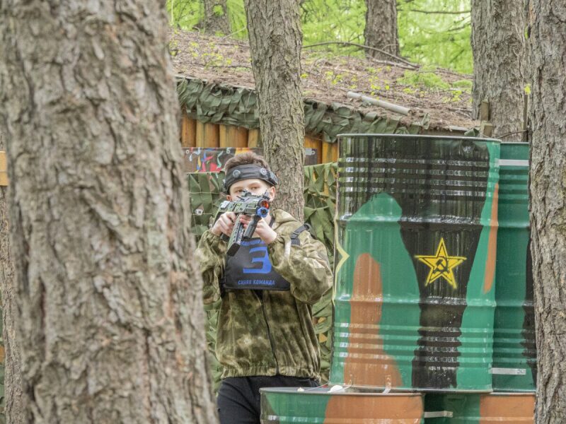 Юный боец LASERWAR ведет прицельный огонь из-за дерева.