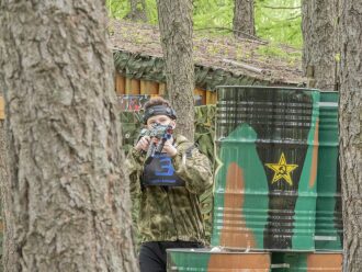 Юный боец LASERWAR ведет прицельный огонь из-за дерева.