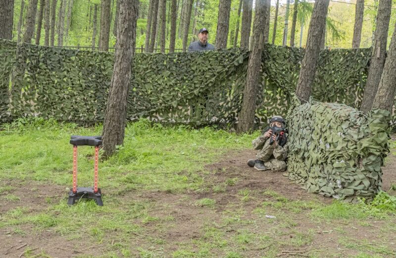 Юный боец LASERWAR ведет огонь из-за маскировочного укрытия.