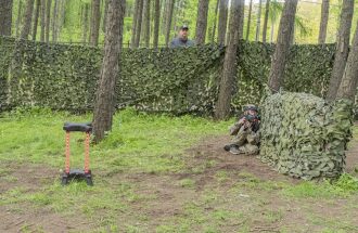 Юный боец LASERWAR ведет огонь из-за маскировочного укрытия.