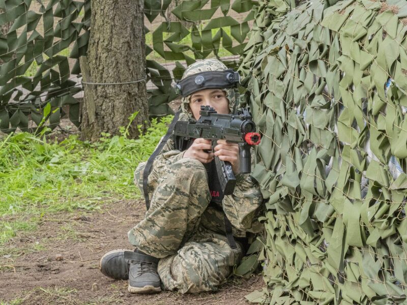 Юный лазертаг-боец LASERWAR в засаде у маскировочной сети.
