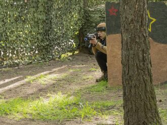 Юный боец LASERWAR прицеливается из-за деревянного укрытия.