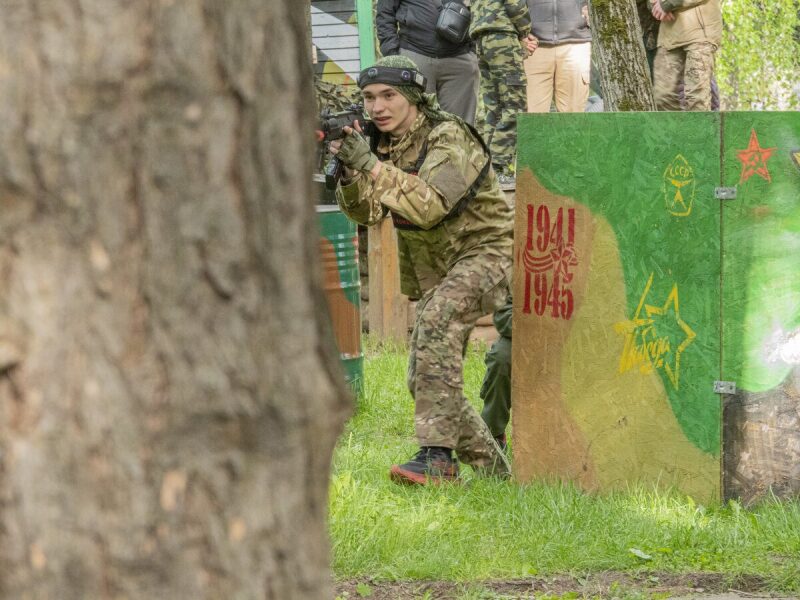 Юный боец LASERWAR с бластером у тематической стены.