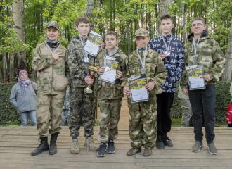 Победители турнира LASERWAR позируют с наградами на деревянной сцене.