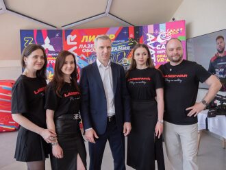 Команда LASERWAR позирует на фоне баннера.