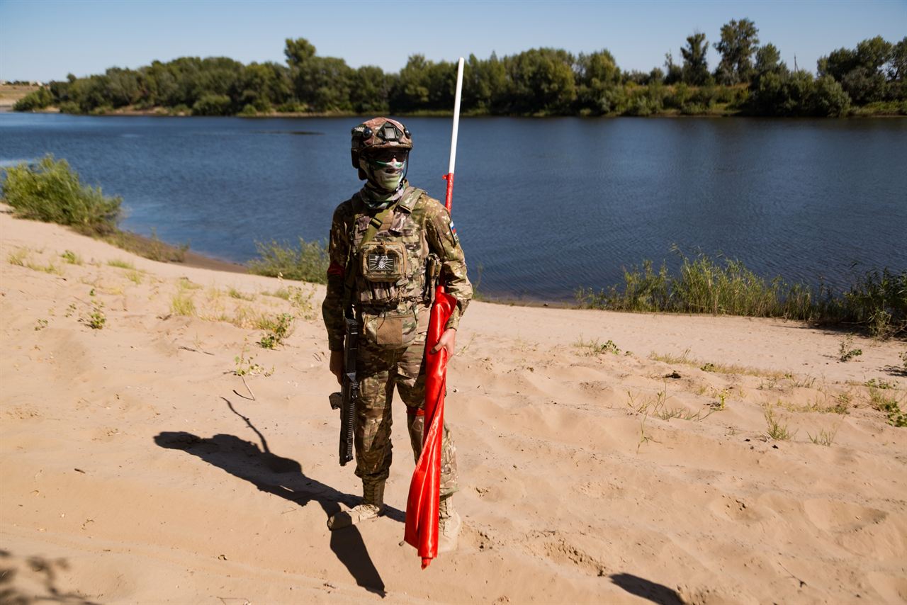 «Зарница 2.0»: один боец с высоким красным флагом у широкой реки