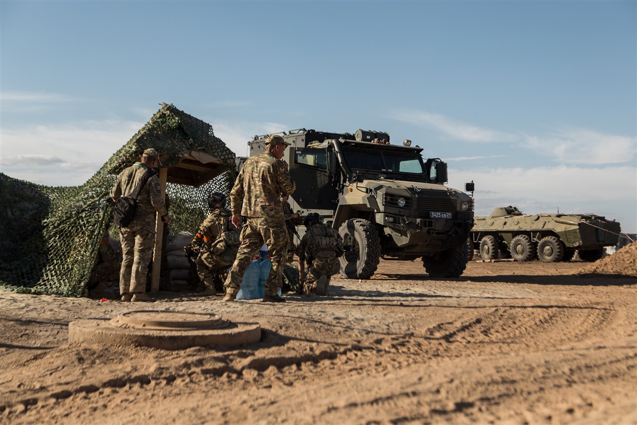 Старшая возрастная категория: Группа у крупного военного грузовика на пыльном поле