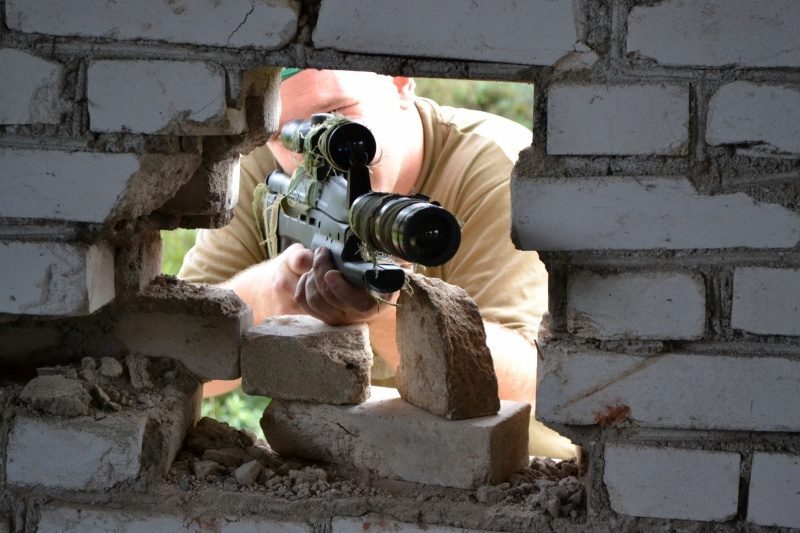 Снайпер LASERWAR выслеживает цель через пролом в стене.