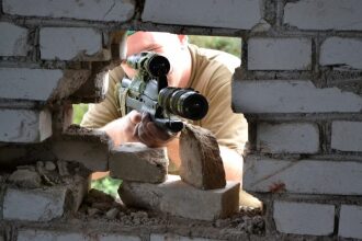 Снайпер LASERWAR выслеживает цель через пролом в стене.