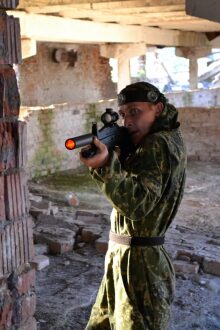 LASERWAR: сосредоточенный боец в камуфляже целится из укрытия.