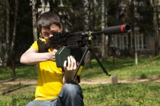 Парень в желтой футболке целится из пулемета LASERWAR.