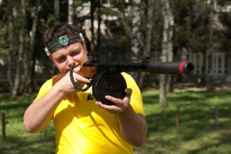 Боец LASERWAR с пулеметом прицеливается в летний день.