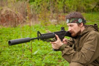 Игрок LASERWAR в камуфляже целится из автомата