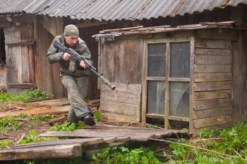 Боец LASERWAR в движении, прицеливается из-за укрытия.