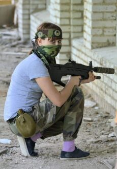 Девушка-боец LASERWAR в маскировке у кирпичной стены
