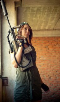LASERWAR: девушка с футуристическим оружием на фоне кирпичной кладки.