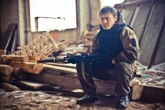 Боец LASERWAR в ожидании у деревянных бревен.
