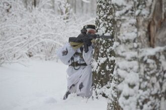 Боец LASERWAR в снайперской позиции за стволом дерева