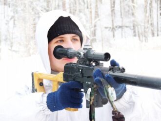 Снайпер в белом камуфляже целится из оружия