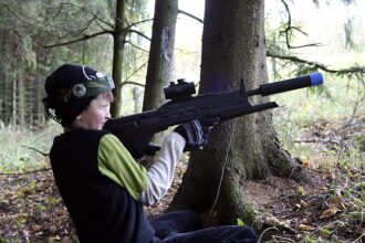 Маленький снайпер LASERWAR в лесу у дерева.