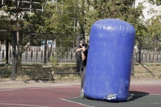 Игрок LASERWAR за синим цилиндрическим укрытием ведет огонь.