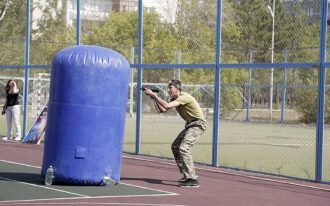 Игрок LASERWAR за синим надувным столбом целится.