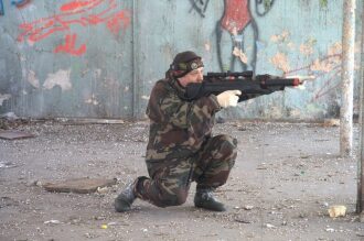 Лазертаг-боец в засаде у стены с граффити
